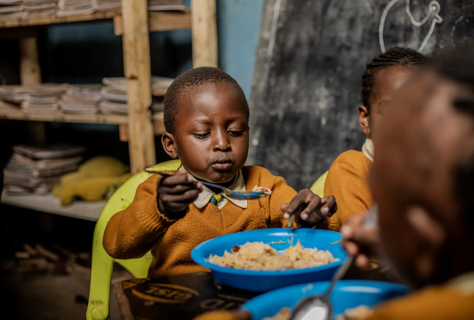 A boy eating his lunch from a blue bowl