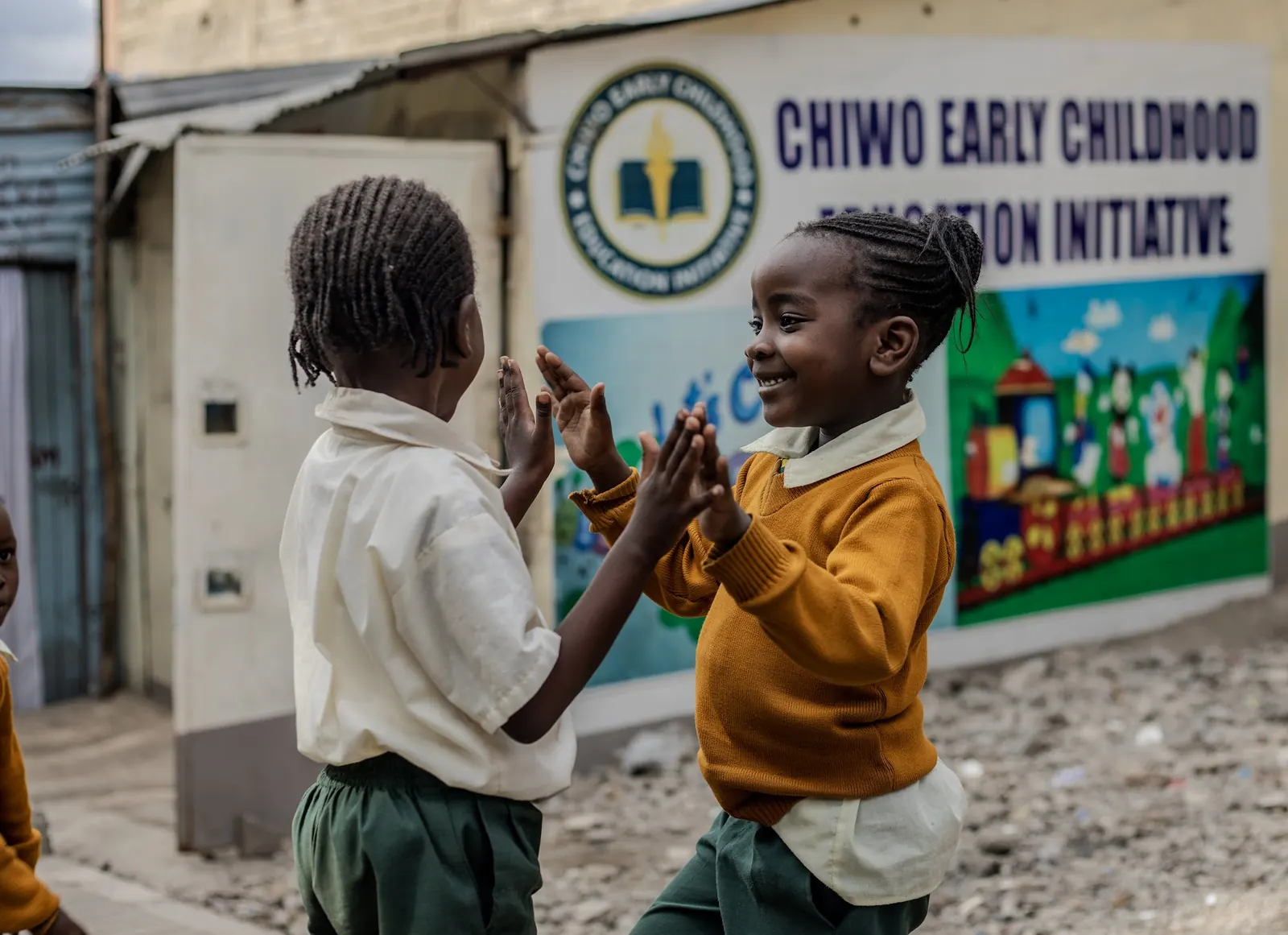 Two girls playing a clapping game outside the school