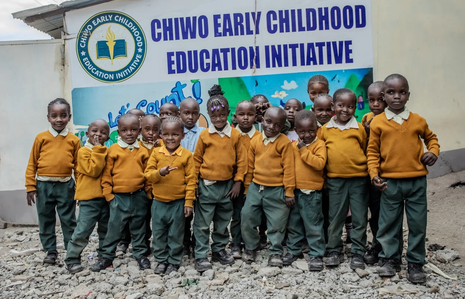 A class of CHIWO pupils standing together in front of the school's sign