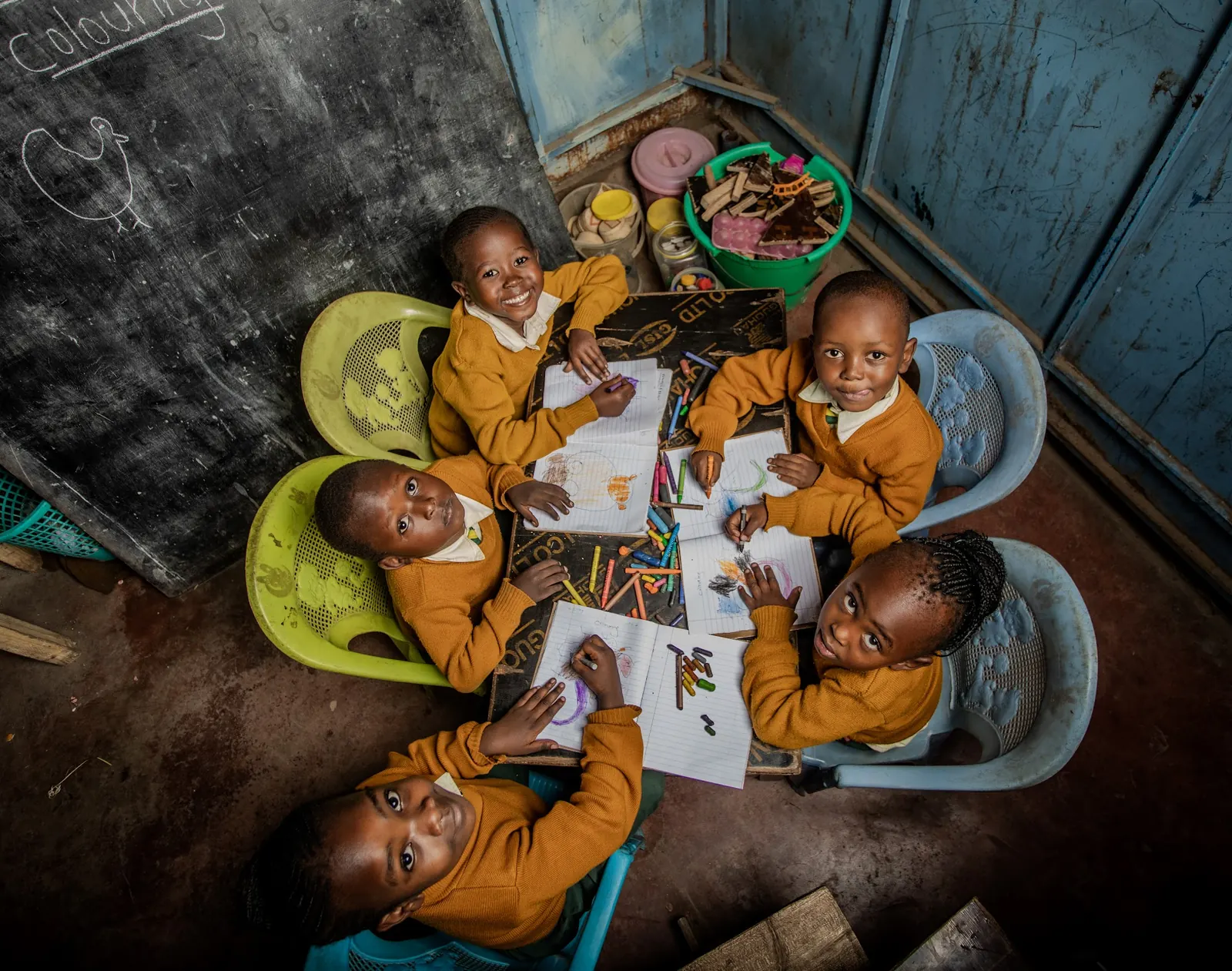Six children colouring around a table, seen from above