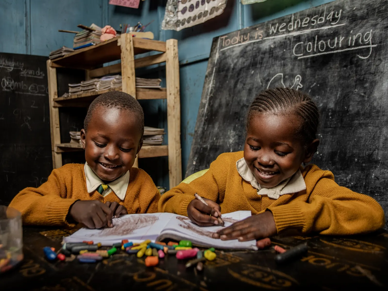 Two children smiling as they colour a picture together