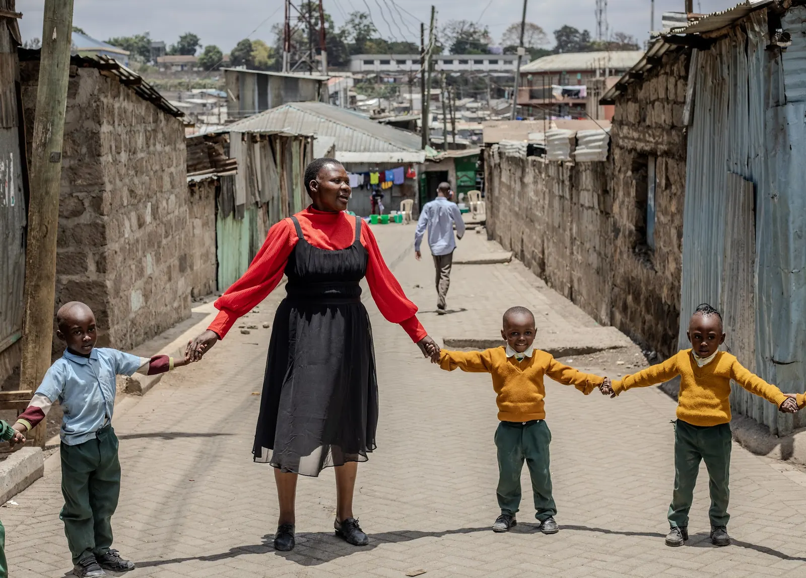 A teacher and children holding hands in a line across the lane