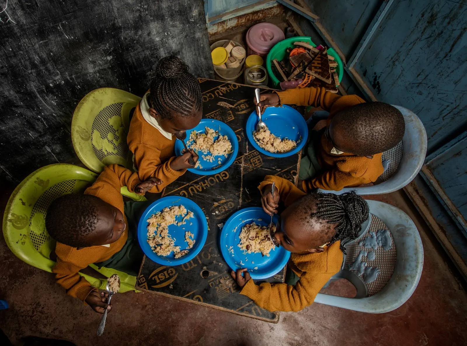 Children eating lunch from blue bowls, seen from above