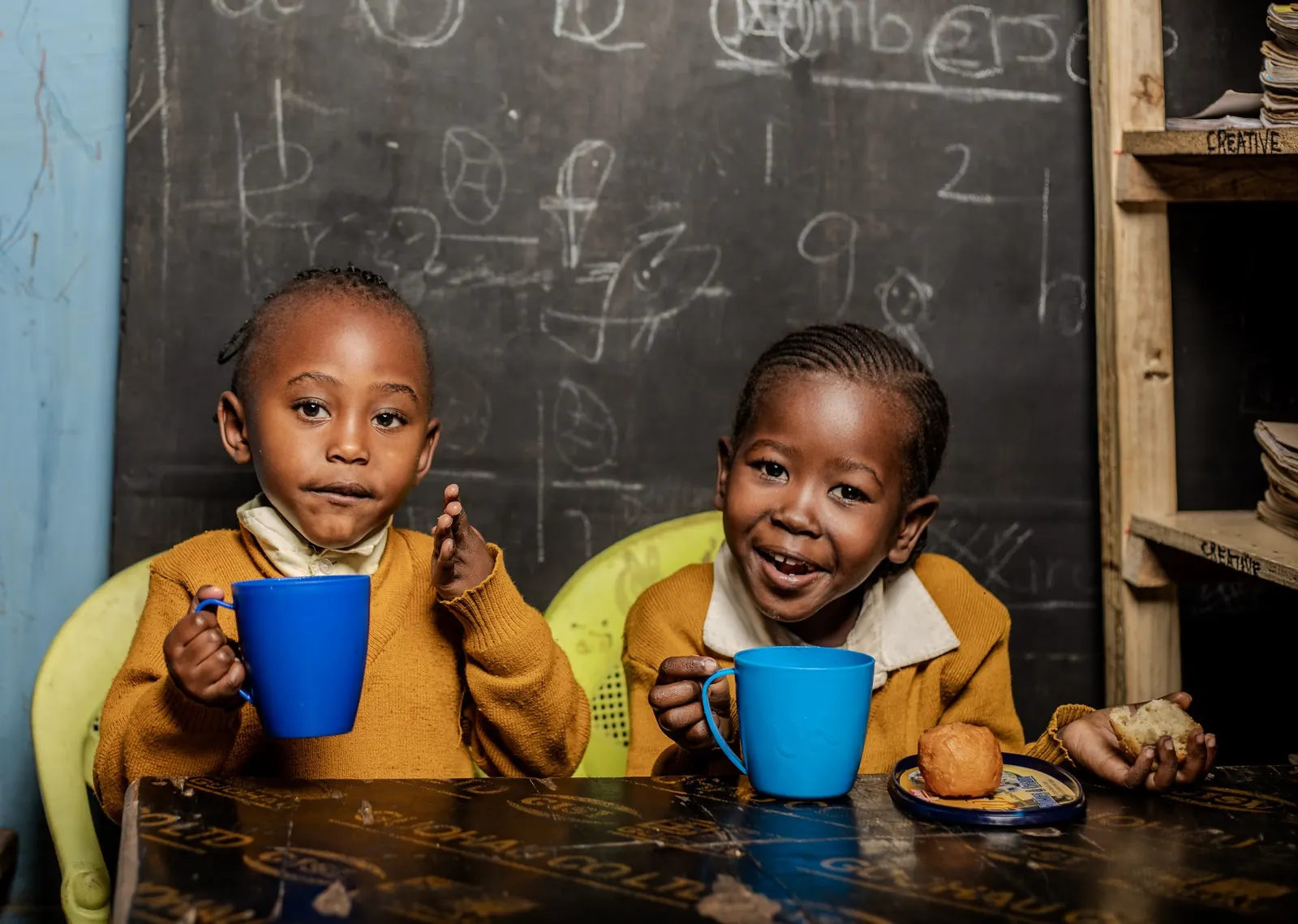 Two girls smiling over their blue cups at tea break