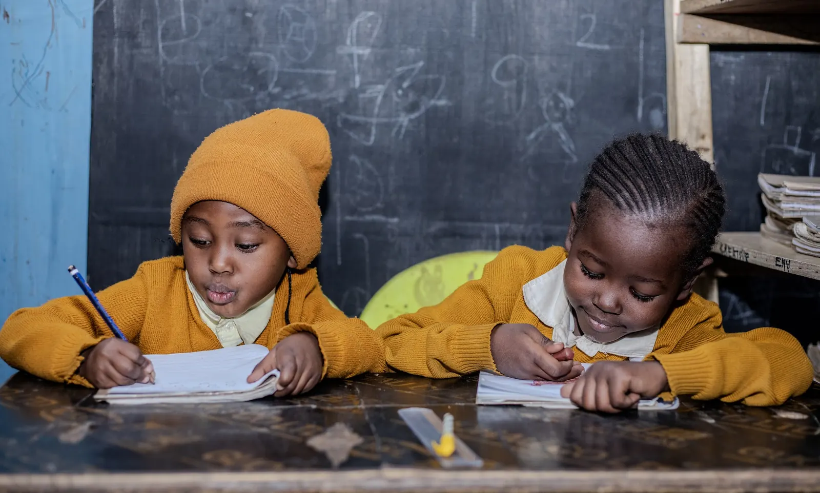 Two children writing carefully in their exercise books
